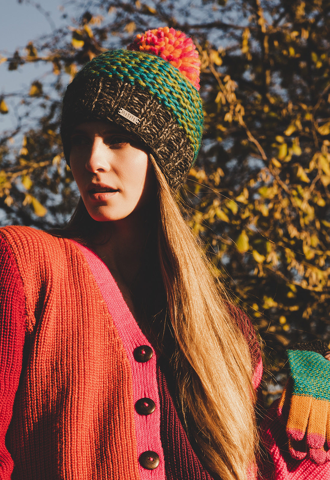 Tashima gloves Fotomodell trägt ein Tushima Bommelmütze, einen Sadar Cardigan und hält die Tushima Handschuhe.